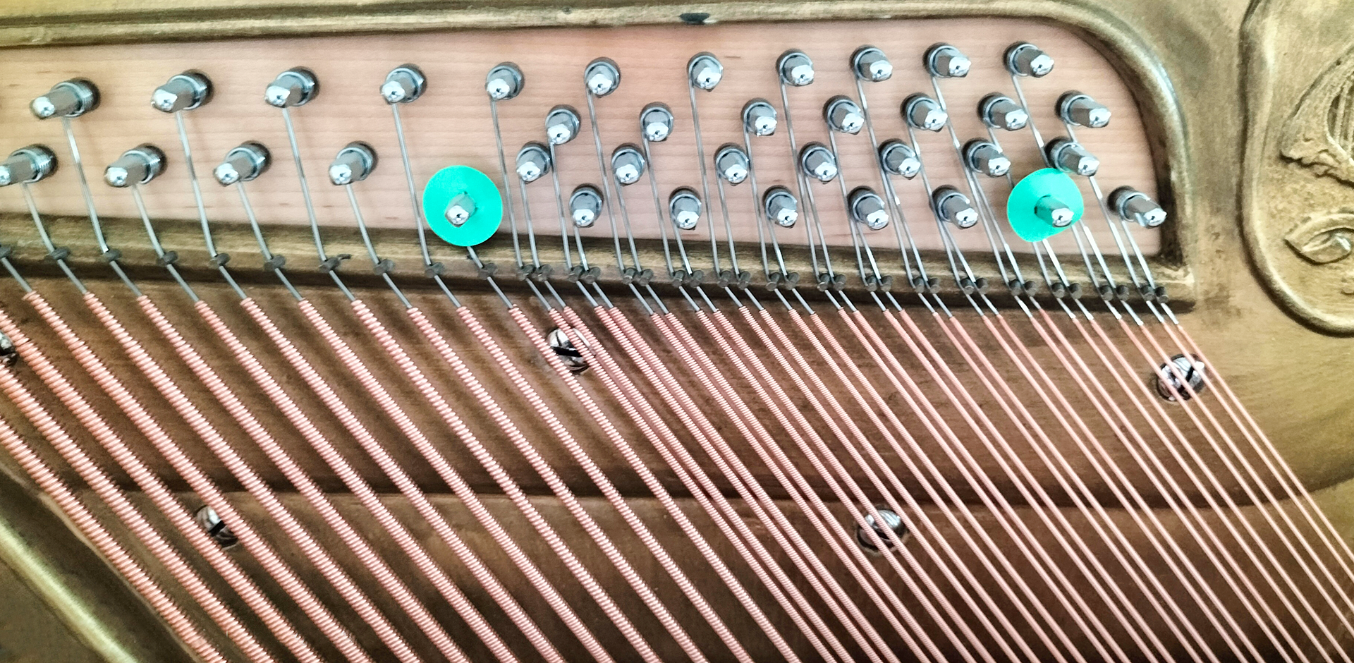 Zdjęcie przedstawia kołki i wkręty ze stali niklowanej, sztabę dociskową mosiężną i ramę żeliwną pianina.