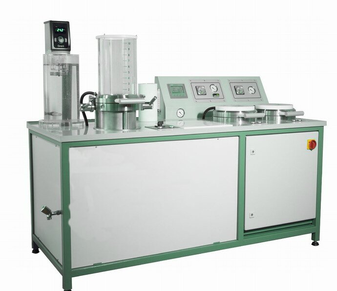 Zdjęcie poglądowe, na którym znajduje się automatyczna formierka. Jej konstrukcja przypomina podłużną, poziomą szafę pancerną, a na jej blacie znajdują się od lewej: elektroniczny czytnik s pokrętłem, umieszczony na okrągłym podwyższeniu szklany zbiornik z podziałką dziesięciolitrową, konsola sterownicza i dwa okrągłe ściski do próbek papieru, za którymi umieszczony jest skośny kokpit do sterowania zaciskami.