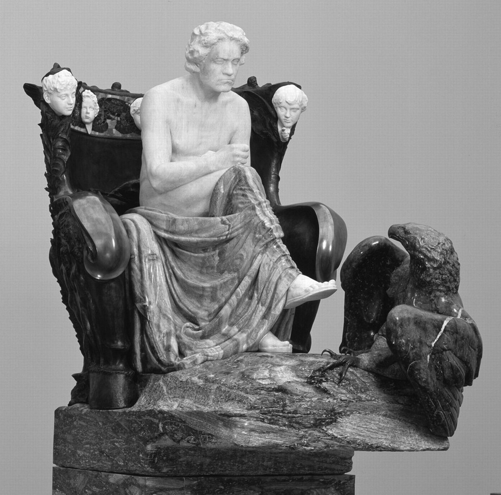 lustracja przedstawia rzeźbę „Beethoven” autorstwa Maxa Klingera. Rzeźba ukazuje marmurową postać siedzącą na bogato zdobionym tronie. Kolana postaci okryte są szatą. Na pierwszym planie ilustracji znajduje się czarny orzeł.