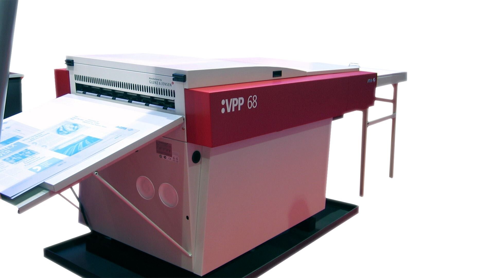 Zdjęcie przedstawia poglądowo przykładową naświetlarkę CtP w ujęciu z ukosa, służącą do bezpośredniego wykonania formy drukowej z pominięciem etapu form kopiowych. Na zdjęciu widoczne jest urządzenie z wysuniętym prostokątnym blatem, na którym umieszcza się formę drukową do naświetlenia. Po przeciwległej stronie urządzenia widoczny jest blat na nogach, na który wysuwa się naświetlona forma drukowa. 