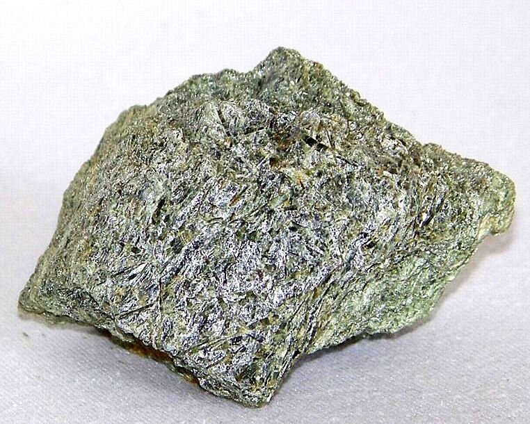 Zdjęcie przedstawia minerał o włóknistej budowie. Ma porowatą powierzchnię. 