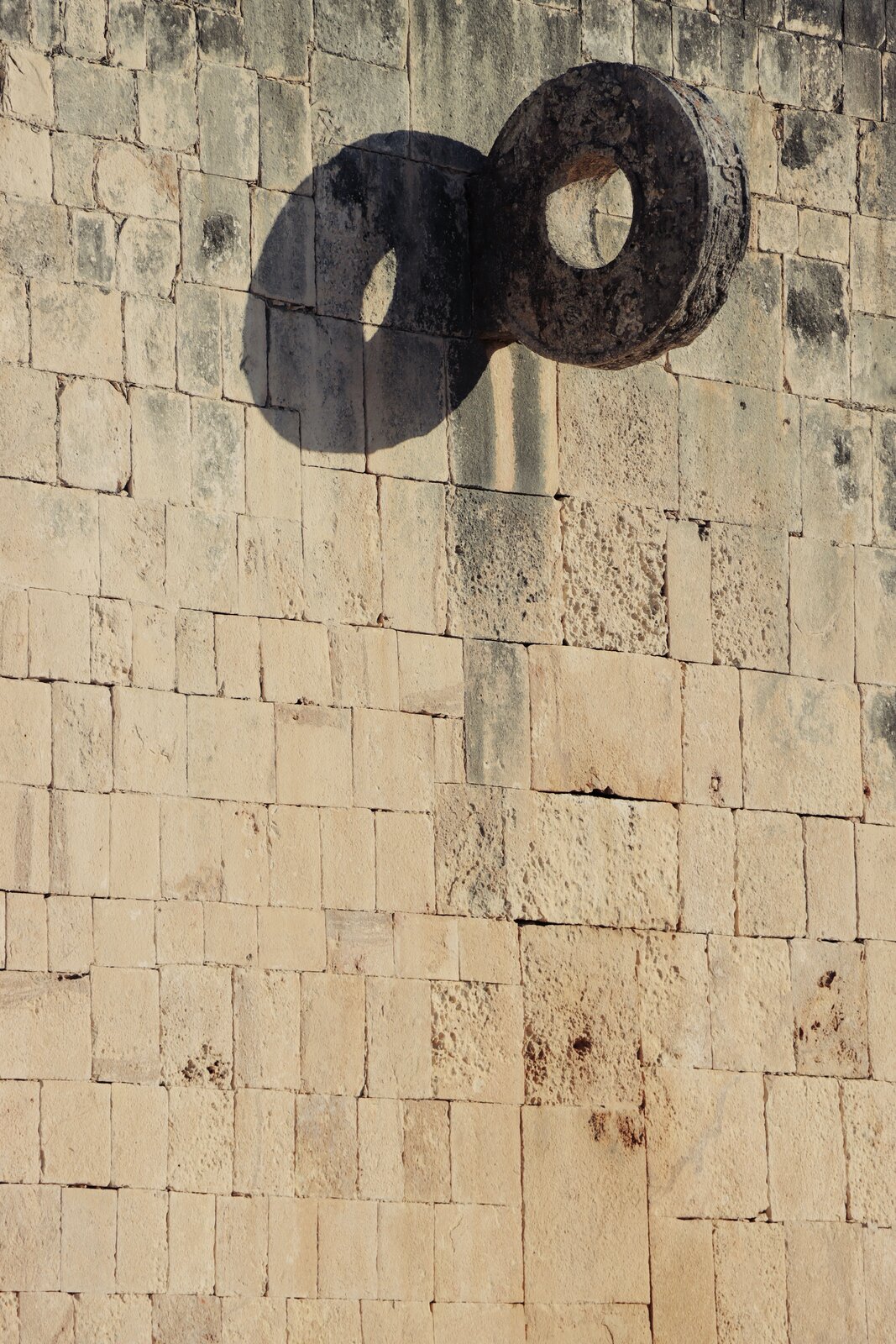 Zdjęcie przedstawia wysoką ścianę złożoną z piaskowych bloków kamiennych różnej wielkości. Materiał został poddany szczotkowaniu, dzięki czemu na jego powierzchni widoczne są linie i wypustki.