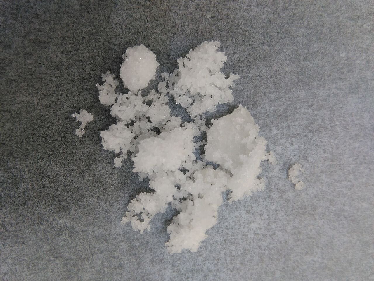 Na zdjęciu pokruszone kryształy o białym kolorze. To wodorotlenek cezu. 