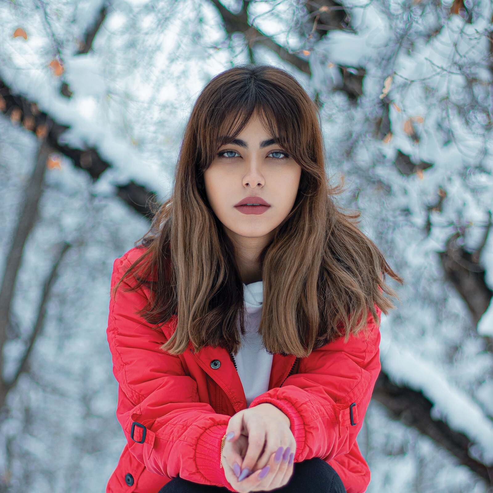 Zdjęcie przedstawia młodą dziewczynę. Jest szczupła i niska. Ma mały nos i niebieskie oczy. Ma również brązowe, długie, rozpuszczone włosy i grzywkę. Jest ubrana w czerwoną kurtkę.