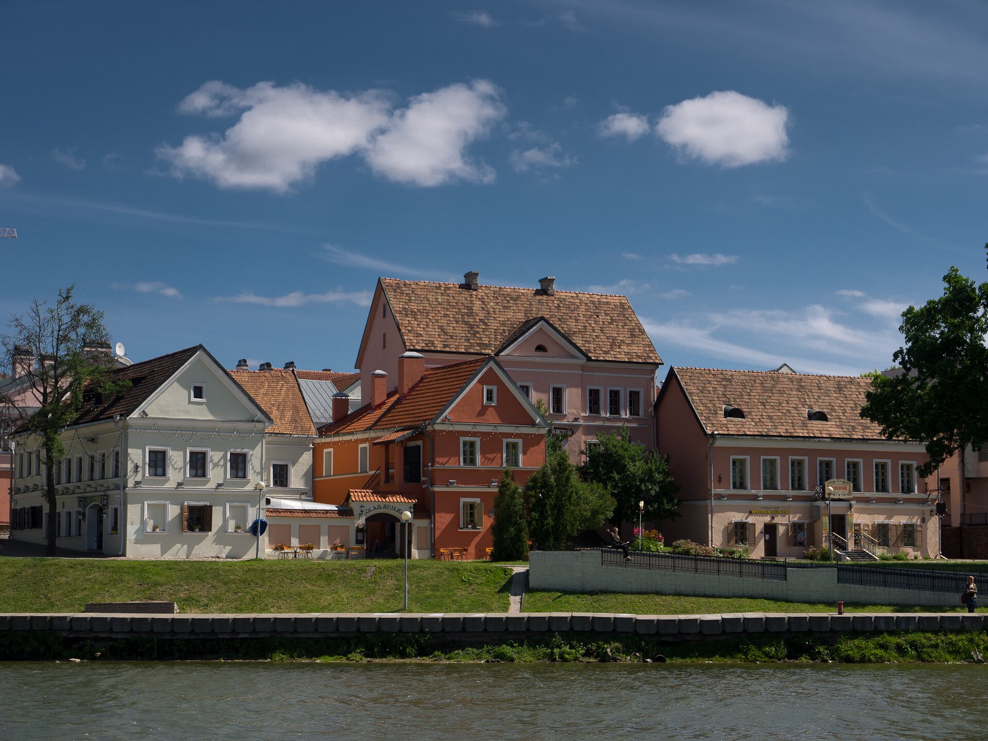 Zdjęcie budynków mieszkalnych trzykondygnacyjnych i dwukondygnacyjnych położonych nad wodą.