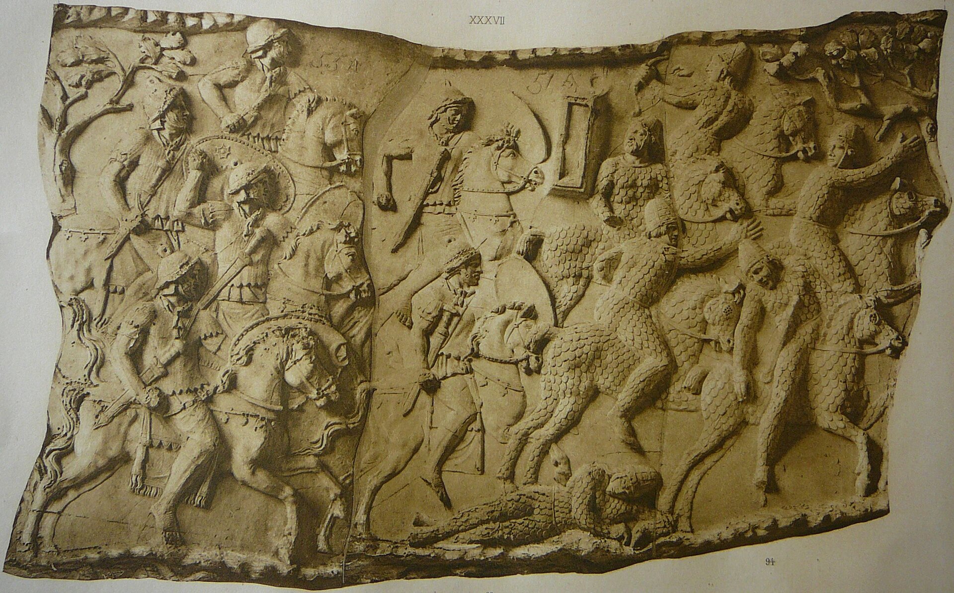 Ilustracja interaktywna przedstawia zdjęcie fragmentu Kolumny Trajana. Ukazuje fragment bitwy Rzymian z Dakami. Po lewej stronie na koniach ukazani są Rzymianie, którzy atakują wroga. Wojownicy na koniach ukazani są rzędowo. Prawa strona przedstawia uciekających Daków. Jedni odwracają się, inni spadają z koni. Na dole leży martwy żołnierz.