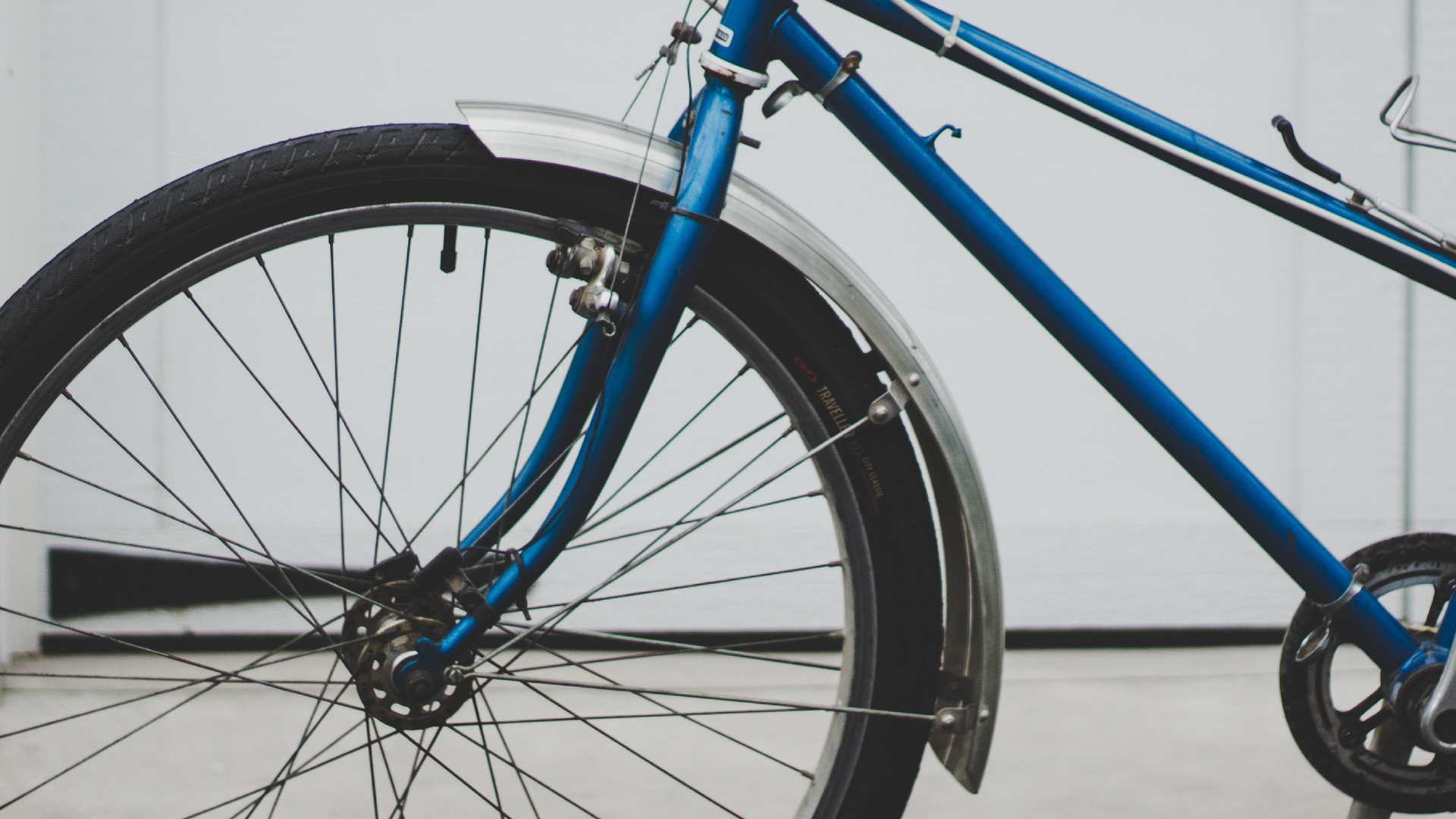 Zdjęcie przedstawia zbliżenie na przednią część roweru. Widoczne jest przednie koło oraz fragment ramy. Na przednim kole założony jest błotnik.