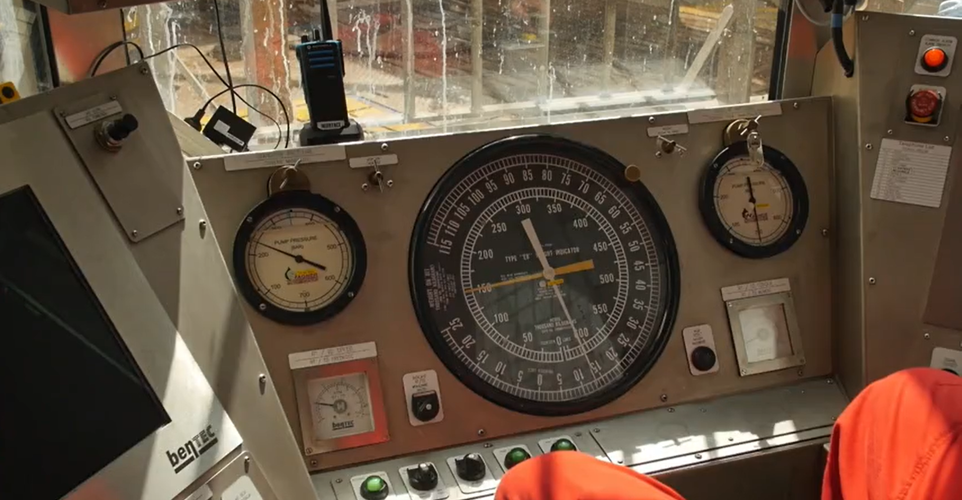 Zdjęcie przedstawia kabinę operatora, w której znajduje się aparatura kontrolno‑pomiarowa. Przed operatorem znajduje się pięć różnych wskaźników o różnym kształcie i rozmiarze.  Dwa mniejsze wskaźniki o kolistym kształcie znajdują się na górze stalowego panelu. Dwa mniejsze wskaźniki w kształcie kwadratu znajdują się w dolnych narożach panelu. Po środku stalowego panelu znajduje się ostatni wskaźnik o kształcie koła, którego średnica  jest równa wysokości panelu. Po lewej stronie znajduje się czarny ekran.  Aparatura kontrolno‑pomiarowa jest to zespół wskaźników, czujników, manometrów oraz innych elementów służących do dostarczania informacji na temat wiercenia. W skład aparatury kontrolno‑pomiarowej wchodzi: Manometr ciśnienia w przewodzie wiertniczym pozwalający na monitorowanie aktualnego ciśnienia w przewodzie wiertniczym, miernik prędkości obrotowej pozwalający na monitorowanie prędkości obrotowej przewodu wiertniczego, ciężarowskaz pozwalający na monitorowanie aktualnego ciężaru na haku wiertniczym oraz nacisku wywieranego na świder , manometr ciśnienia w przestrzeni pierścieniowej pozwalający na monitorowanie aktualnego ciśnienia w przestrzeni pierścieniowej między przewodem wiertniczym a kolumną rur okładzinowych, miernik momentu obrotowego pozwalający na monitorowanie aktualnego momentu obrotowego przewodu wiertniczego oraz Ekran wizualizujący historyczne dane z wiercenia w czasie rzeczywistym - Urządzenie pokazujące parametry takie jak: ciężar na haku, nacisk na świder, prędkość i moment obrotowy przewodu, ilość wpływającej i wypływającej płuczki, ciśnienie pomp płuczkowych, postęp wiercenia i wiele innych ważnych parametrów ze względu na prędkość i bezpieczeństwo procesu wiercenia.