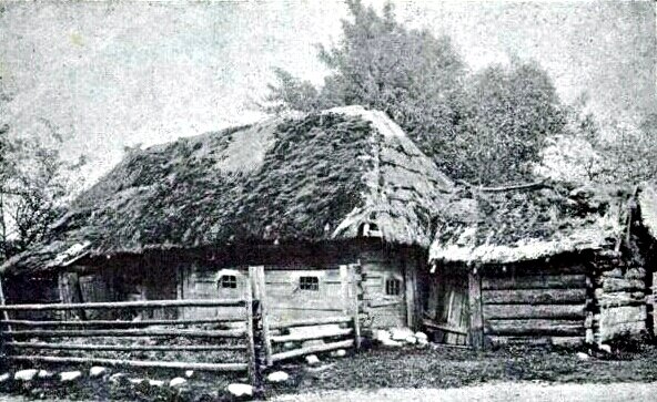 Ilustracja przedstawia wiejską chatę, której dach wykonany jest ze strzechy. Do chaty przylega waląca się szopa. Wokół domu jest płot wykonany z belek. 