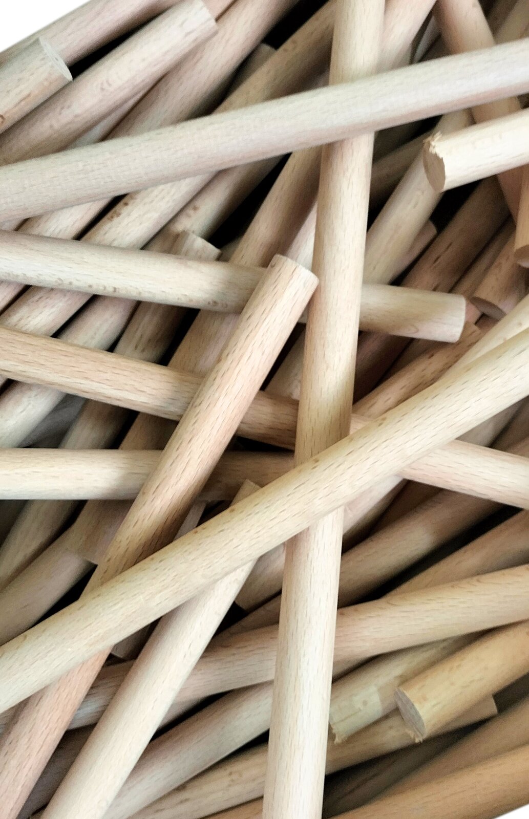 Zdjęcie przedstawia dyble bukowe. Widoczne są cylindryczne dyble w kolorze jasnobeżowym, położone jeden na drugim w nieregularnym układzie.