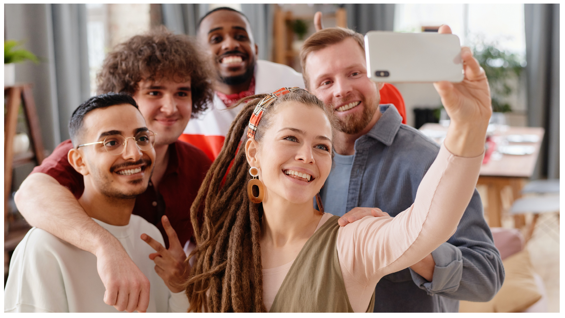 Ilustracja przedstawia grupę osób uśmiechających się i pozujących do zdjęcia robionego przez jedną z nich na wyciągniętej ręce.
