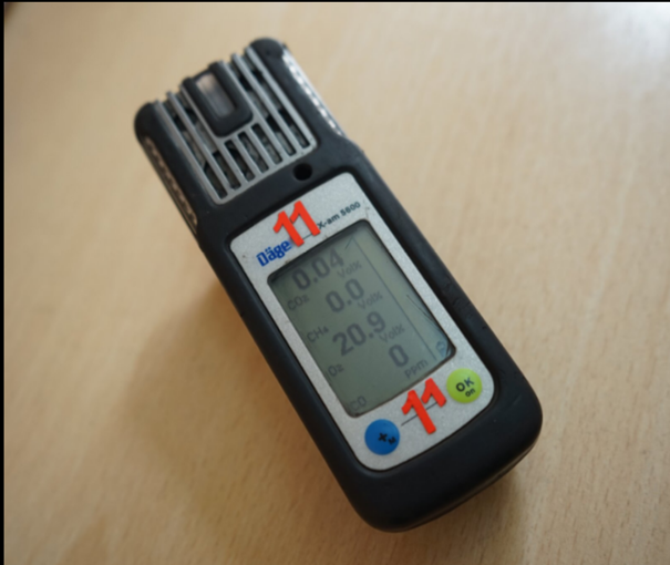 Widok na grafikę w powiększeniu. Grafika przedstawia czujnik powietrza. Jest on o kształcie prostopadłościanu. Na przedniej ścianie znajduje się duży wyświetlacz. Na wyświetlaczu widoczne są cyfry.