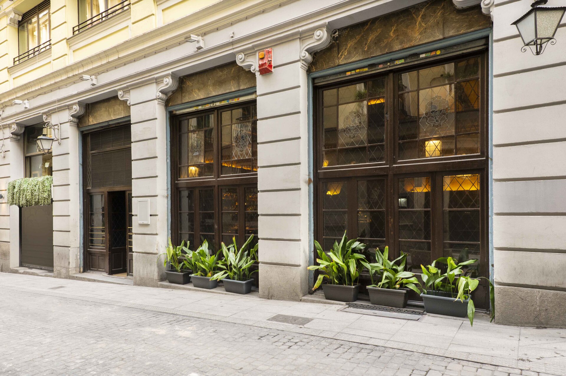 Zdjęcie przedstawia obiekt usługowy z dużymi oknami podzielonymi na kilkanaście małych szklanych kwadratów o ciemnych ramach.