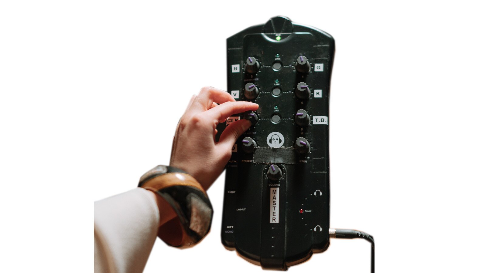 Na zdjęciu widać prostokątne, czarne urządzenie, ze ściętymi narożnikami do połączenia komputera z analogowym sprzętem grającym. Na urządzeniu widoczne są włączniki, pokrętła oraz potencjometry. Po lewej stronie widoczna jest ręka dotykająca jednego z pokręteł na urządzeniu.