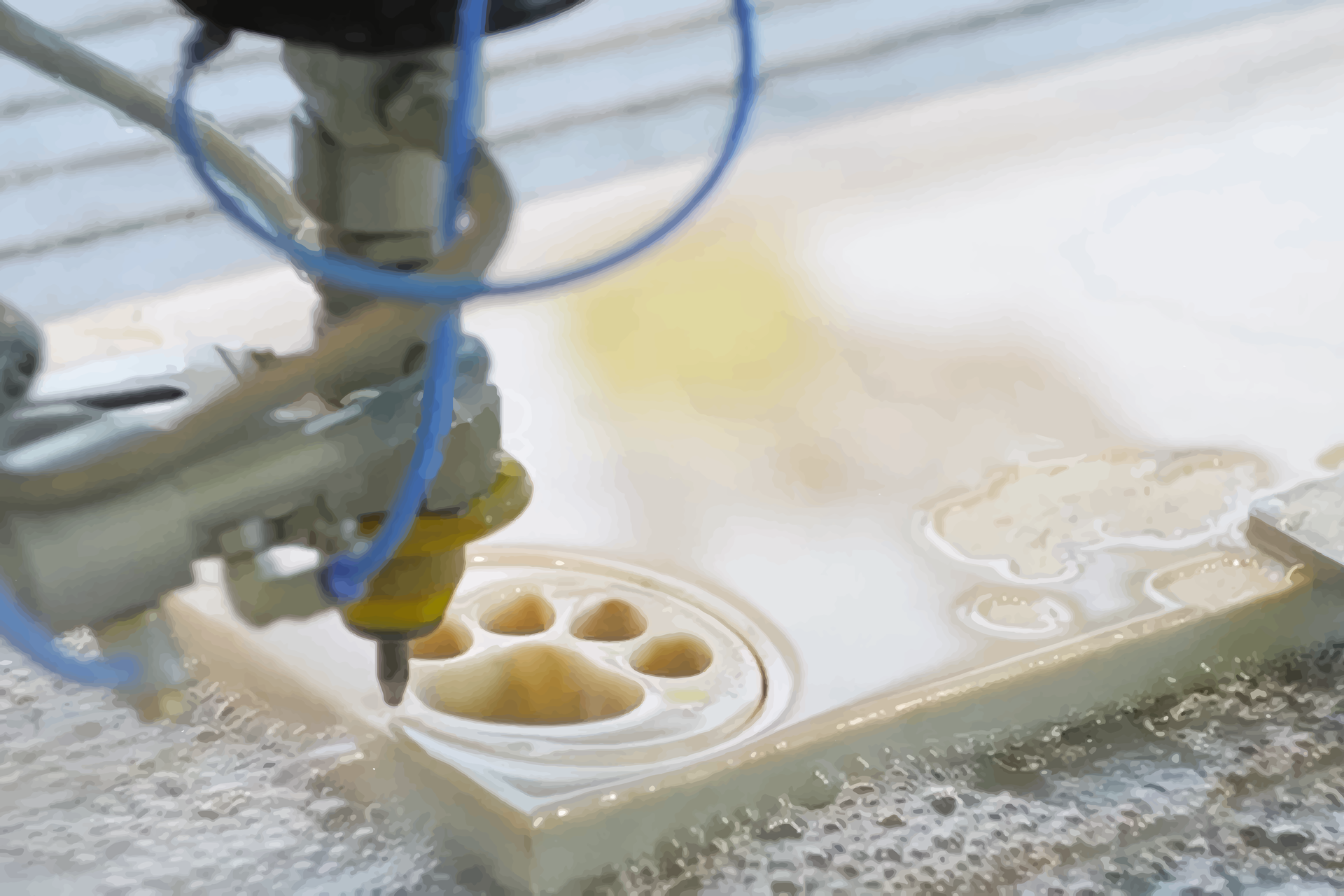  Zdjęcie przedstawia wycinanie kształtów za pomocą strumienia wody. Nad kamienną płytą z wyciętym śladem łapy psa widoczna jest dysza urządzenia tnącego.