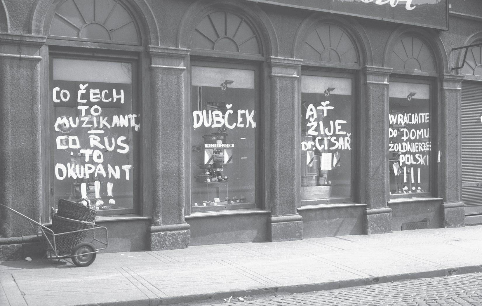 Zdjęcie przedstawia witrynę sklepową, na której są namalowane napisy w języku czeskim.