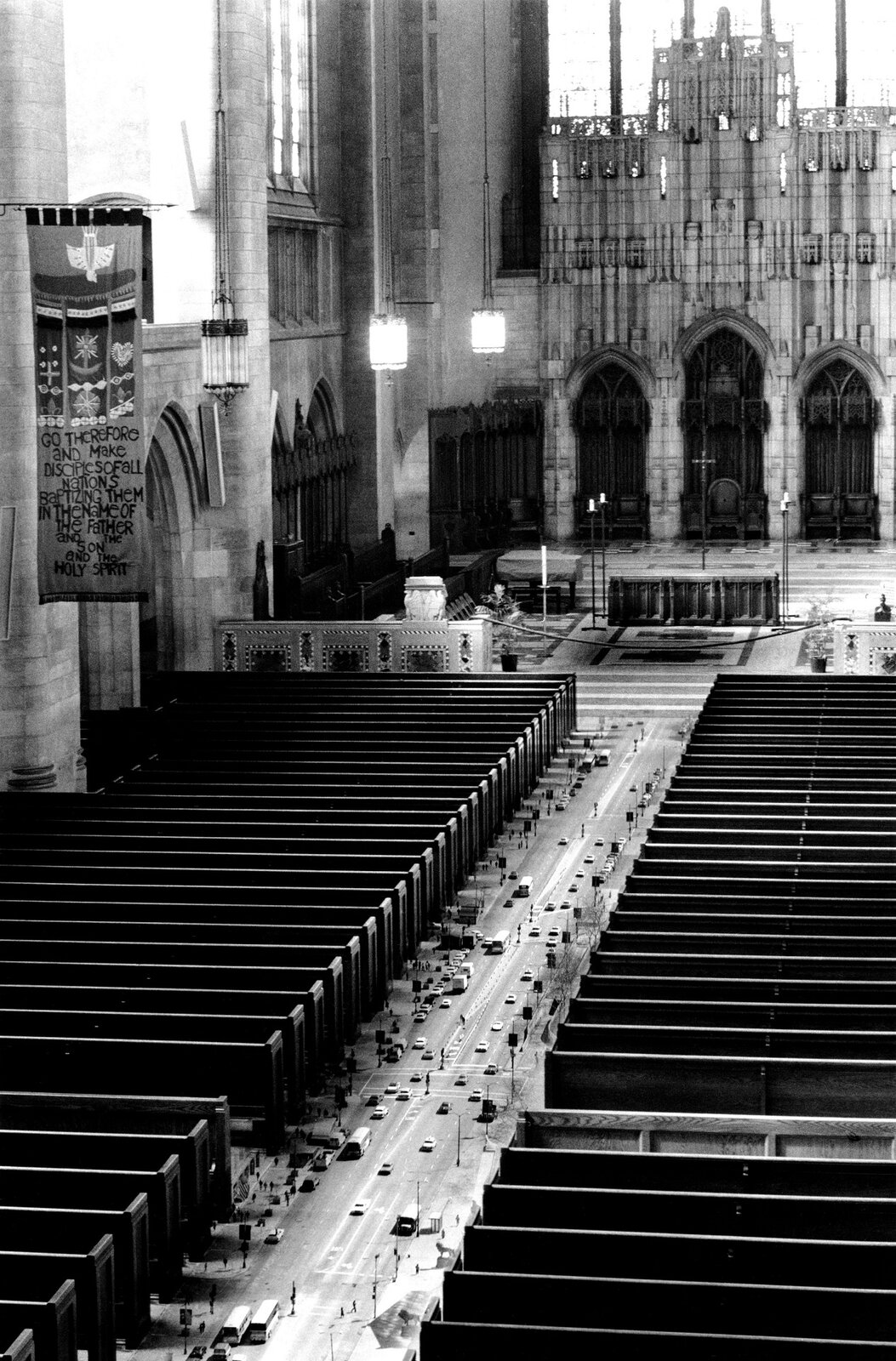 Praca autorstwa Scotta Muttera [czytaj: skota matera] pod tytułem „Nawa kościoła” przedstawia widok na wnętrze dużego kościoła, w którym pomiędzy ławkami, na posadzce odbywa się ruch uliczny – jest to fotokolaż – na fotografię wnętrza kościoła nałożone zostało zdjęcie ruchu ulicznego z dwukierunkową drogą dwupasmową, przez którą przejeżdżają liczne pojazdy.  Ławki kościelne są duże, sprawiają wrażenie budynków umieszczonych po obu bokach drogi. Z przodu widoczna jest główna część kościoła z licznymi zdobieniami – łukami ściennymi, ozdobnymi rzeźbieniami oraz zwisającymi lampami. 