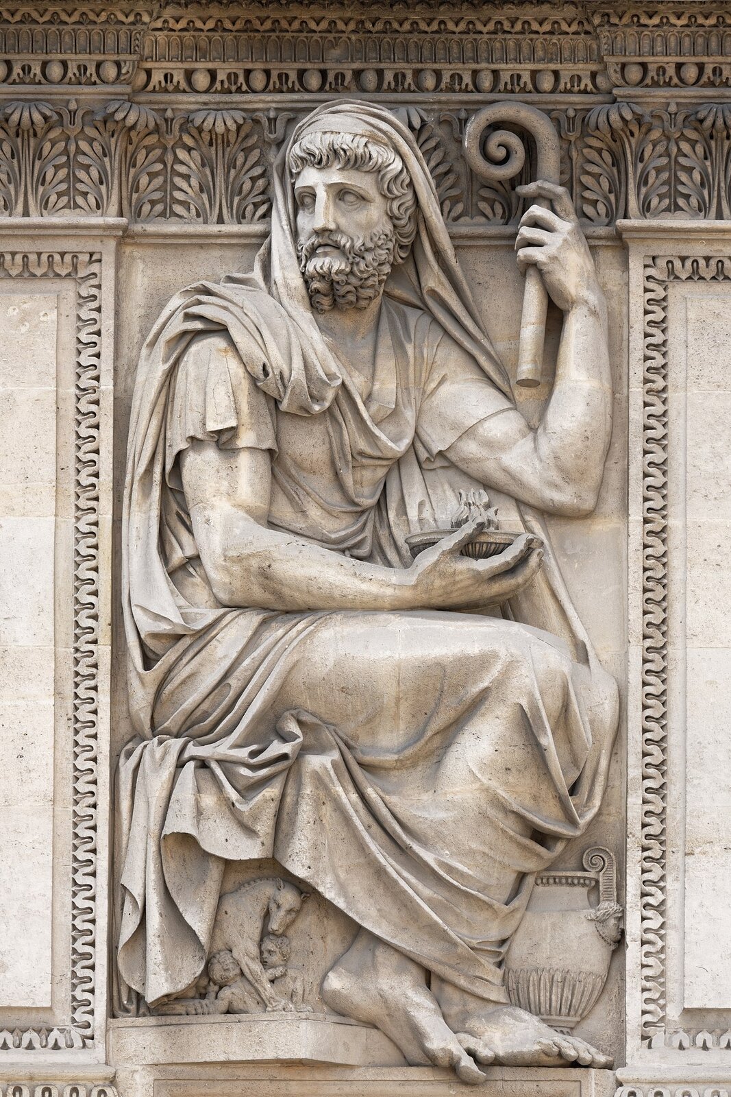 Płaskorzeźba wykonana z białego kamienia prezentuje mężczyznę w średnim wieku, odzianego w luźną szatę, która częściowo zarzucona jest na jego głowę. Mężczyzna ma kręcone włosy oraz brodę. Przedstawiony jest w pozycji siedzącej. Jego twarz skierowana jest w prawą stronę; w lewej ręce trzyma krótką laskę, a w prawej naczynie, w którym tli się niewielki płomień. U stóp mężczyzny z prawej strony stoi dzban, po lewej zaś leży wilczyca z dwoma małymi chłopcami. Dookoła mężczyzny wykonano zdobienia, w formie motywów roślinnych.