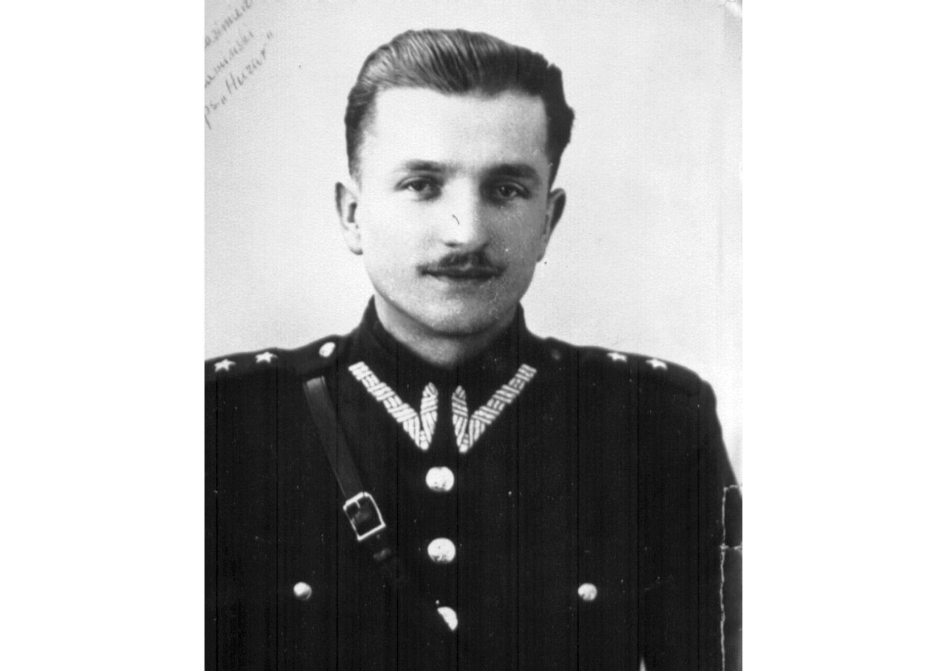 Fotografia portretowa Kazimierza Kamieńskiego, pseudonim „Huzar”. Mężczyzna o pociągłej, szczupłej twarzy z ciemnym wąsikiem. Włosy ciemne, krótkie, zaczesane do góry. Ubrany w mundur.