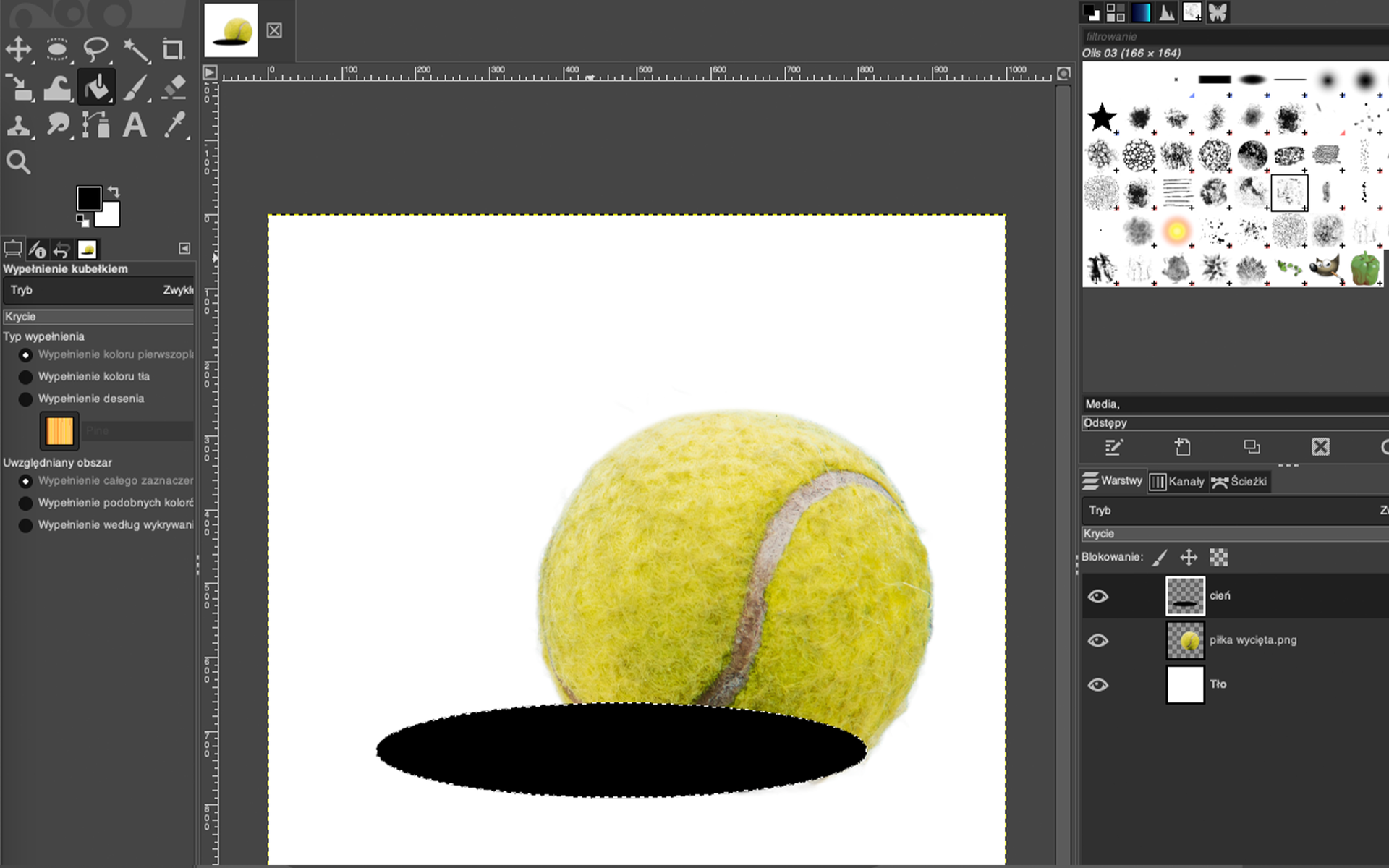 Ilustracja przedstawia okno programu. Po lewej stronie jest panel dotyczący Wypełnienie kubełkiem. W obszarze roboczym jest piłka tenisowa na białym tle. W dolnej części po jej lewej stronie jest czarna elipsa, częściowo zasłania ona dolną część piłki. Po prawej stronie jest panel dotyczący warstw. 