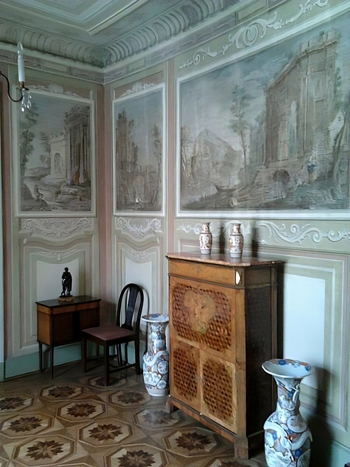 Kliknij, aby powiększyć. Zdjęcia przedstawiają: z lewej strony fasada Pałacu Myślewickiego w Łazienkach Królewskich w Warszawie, z prawej strony malowidła ścienne z 1778 roku w Pałacu Myślewickim autorstwa Antoniego Herliczki. Na lewo znajduje się wygląd fasady Pałacu Myślewickiego w Łazienkach Królewskich w Warszawie. Składa się z trzykondygnacyjnego korpusu głównego i skrzydeł ugiętych ćwierć koliście według wzorów chińskich. Przez całą wysokość korpusu głównego pośrodku biegnie nisza wejściowa, w której kryją się dwie absydy z rzeźbami Jakuba Monaldiego, przedstawiającymi Zefira i Florę. Na prawo jest wygląd pomieszczenia w Pałacu Myślewickim w Łazienkach Królewskich w Warszawie z malowidłami ściennymi Antoniego Herliczki, ukazującymi ruiny antycznych budowli. Całość wnętrza dopełniają chińskie wazy i meble.