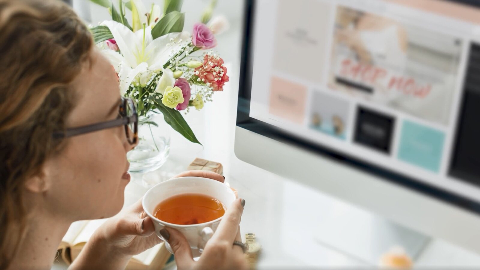 Ilustracja przedstawia młodą kobietą, która siedzi przed ekranem laptopa, trzymając w ręku filiżankę herbaty.