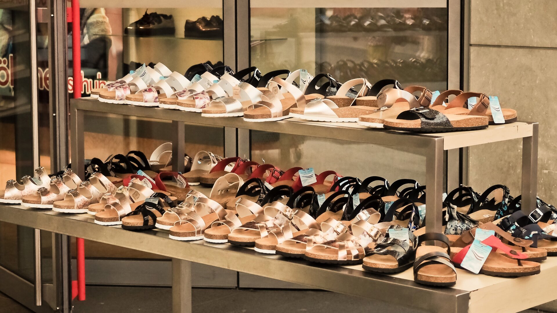 Zdjęcie przedstawia półkę z sandałami sklepie obuwniczym.