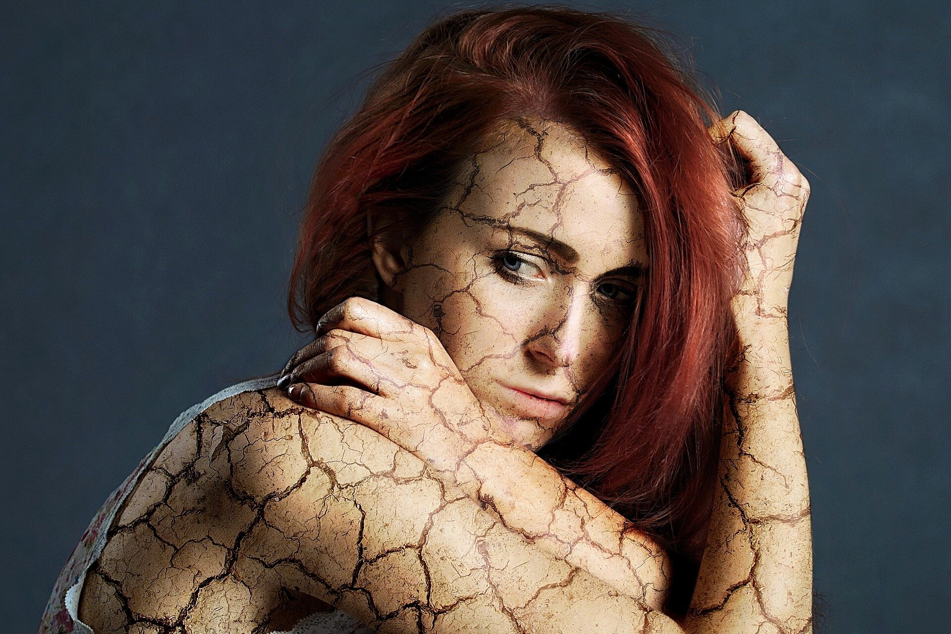 Zdjęcie przedstawia kobietę. Skóra kobiety jest mocno popękana, jak wysuszona gleba. 