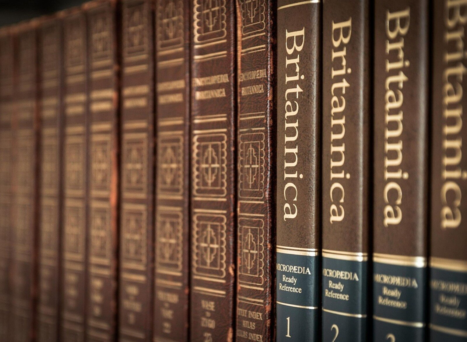 Zdjęcie przedstawia rząd książek w twardych, brązowych oprawach z tłoczeniami w kolorze złota. Pierwsze cztery książki od prawej strony mają na grzbiecie napis Britannicai są ponumerowane od 1 do 4