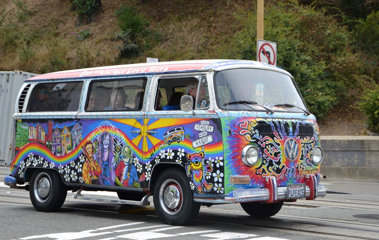 Zdjęcie przedstawia wana marki  volkswagen  [czytaj: folkswagen] zwanego ogórkiem, jadącego ulicą. Samochód jest pomalowany ręcznie w kwiaty i motywy roślinne. Nad kwiatami wije się tęcza, po której jedzie wan, przed nim wielkie, żółte słońce, za słońcem kolorowe domki. Na środku malowidła znajdują się trzy postacie ludzi, ukazane do pasa są to idole hippisów między innymi: Jimmy Hendrix [czytaj: dżimi henriks], Janis Joplin [czytaj: dżenis dżoplin] i mężczyzna o siwych włosach i gęstej brodzie. W wanie siedzą ludzie. W tle pokryte zielenią zbocze góry.