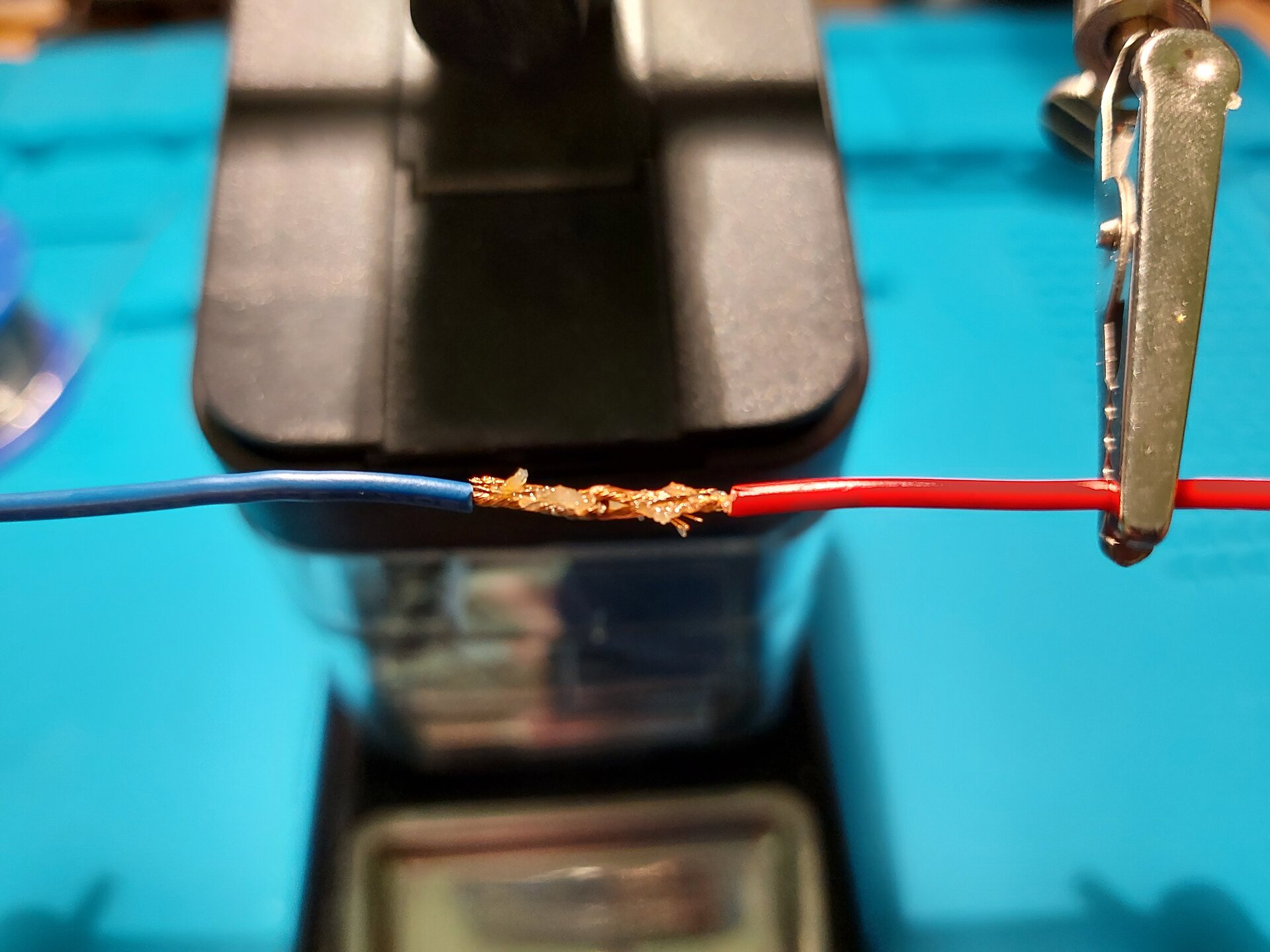 Zdjęcie przedstawia 2 przewody z usuniętą izolacją tym samym odsłaniając miedziane wnętrze, oba wygięte w haczyk założono na siebie i skręcono, następnie nałożono pastę.