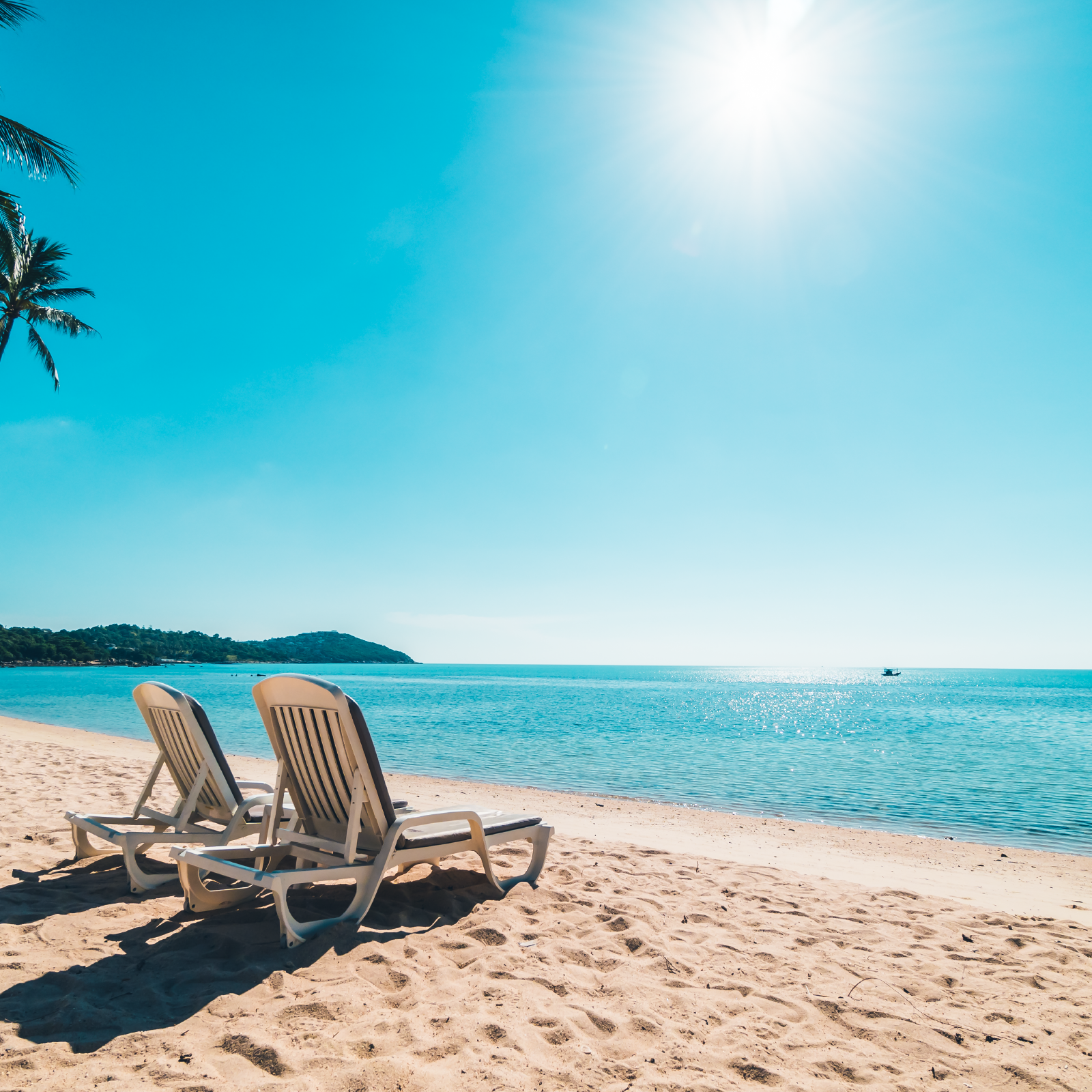 Zdjęcie przedstawia słoneczną plażę, na której stoją obok siebie dwa leżaki. 