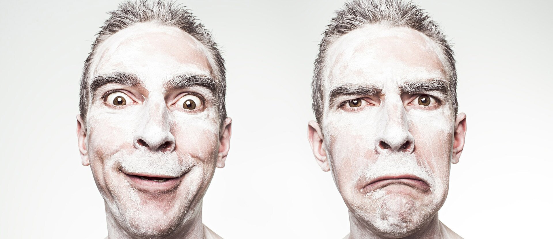 Fotografia przedstawia dwie twarze tego samego mężczyzny, ale wyrażają skrajne emocje. Twarz po lewej stronie wyraża zadowolenie i podziw. Oczy są okrągłe, wytrzeszczone, usta uśmiechnięte. Druga twarz wyraża złość, usta są wykrzywione w dół, oczy półprzymknięte. Mężczyzna ma krótkie włosy i bujne brwi, jego twarz wygląda tak, jakby była białym proszkiem.
