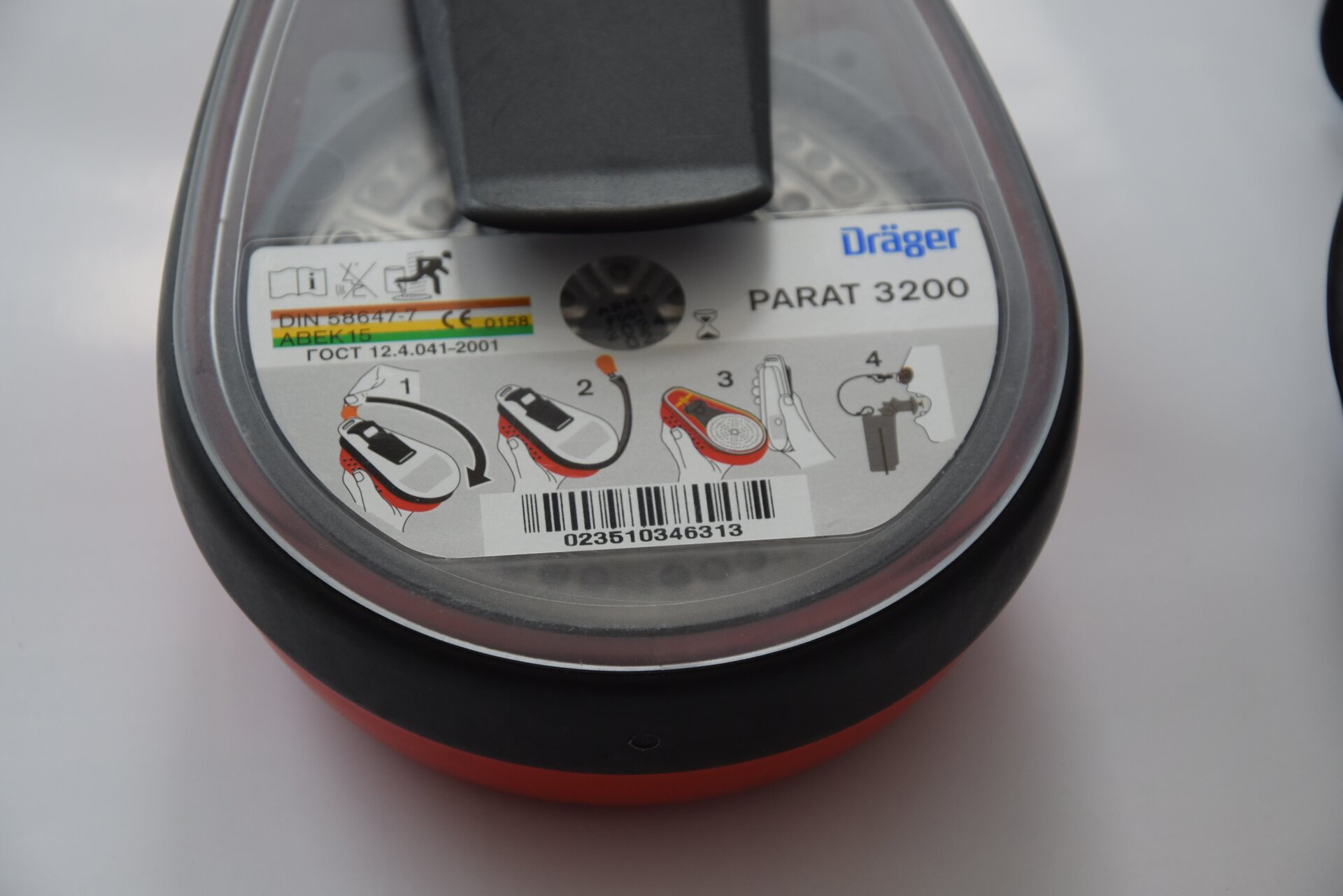 Na zdjęciu widoczny jest sprzęt oczyszczający w formie ustnika i zacisku na nos. Widoczne na zdjęciu urządzenie jest w kształcie łzy. Na górnej podstawie urządzenia znajduje się naklejka z krokami postępowania.  W pierwszym kroku z górnej części urządzenia odrywane jest zabezpieczenie. W drugim kroku prostowana jest czarna rurka znajdująca się po obwodzie urządzenia. W trzecim kroku wyciągany jest ustnik. W czwartym kroku ustnik znajduje się w ustach a zatyczka w nosie.Z noku widoczny jest opis modelu: Parat trzy tysiące dwieście.Poniżej zdjęcia w prawym dolnym rogu widoczny jest przycisk odtwarzania. Tekst nagrania jest zgodny z tytułem zdjęcia.