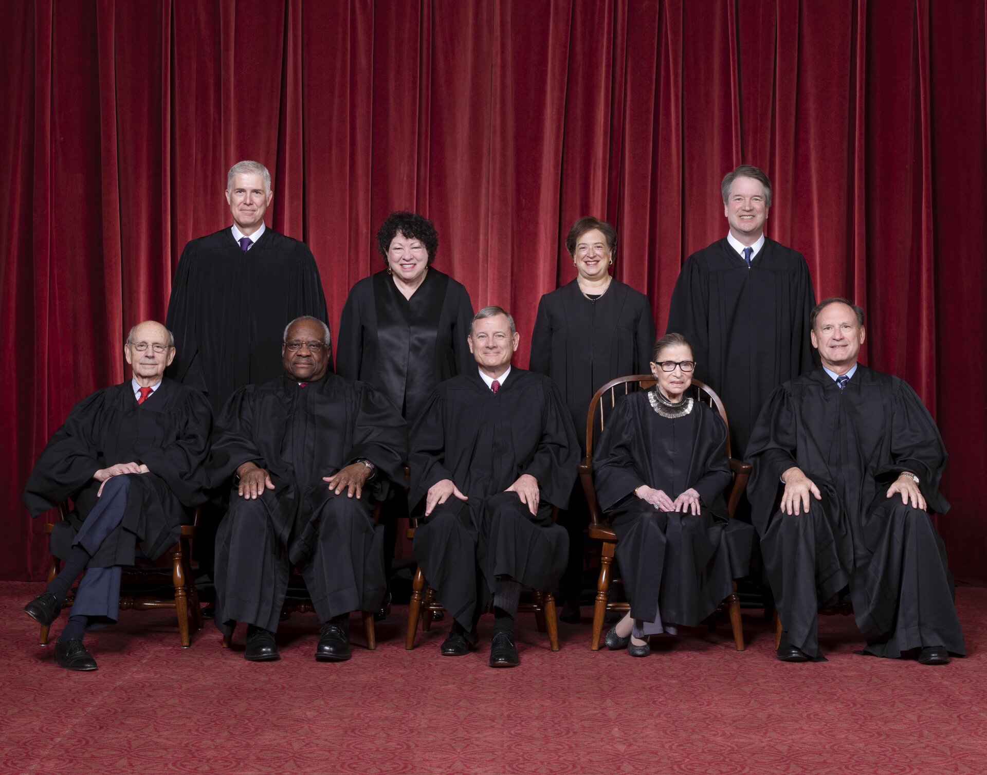 Zdjęcie przedstawia grupę ludzi w czarnych togach sędziowskich. Są to trzy kobiety i sześciu mężczyzn. Ludzie są w dwóch rzędach. W pierwszym rzędzie siedzi pięć osób (jedna kobieta i czterech mężczyzn). Za ich plecami stoi czwórka osób - dwie kobiety i dwóch mężczyzn.