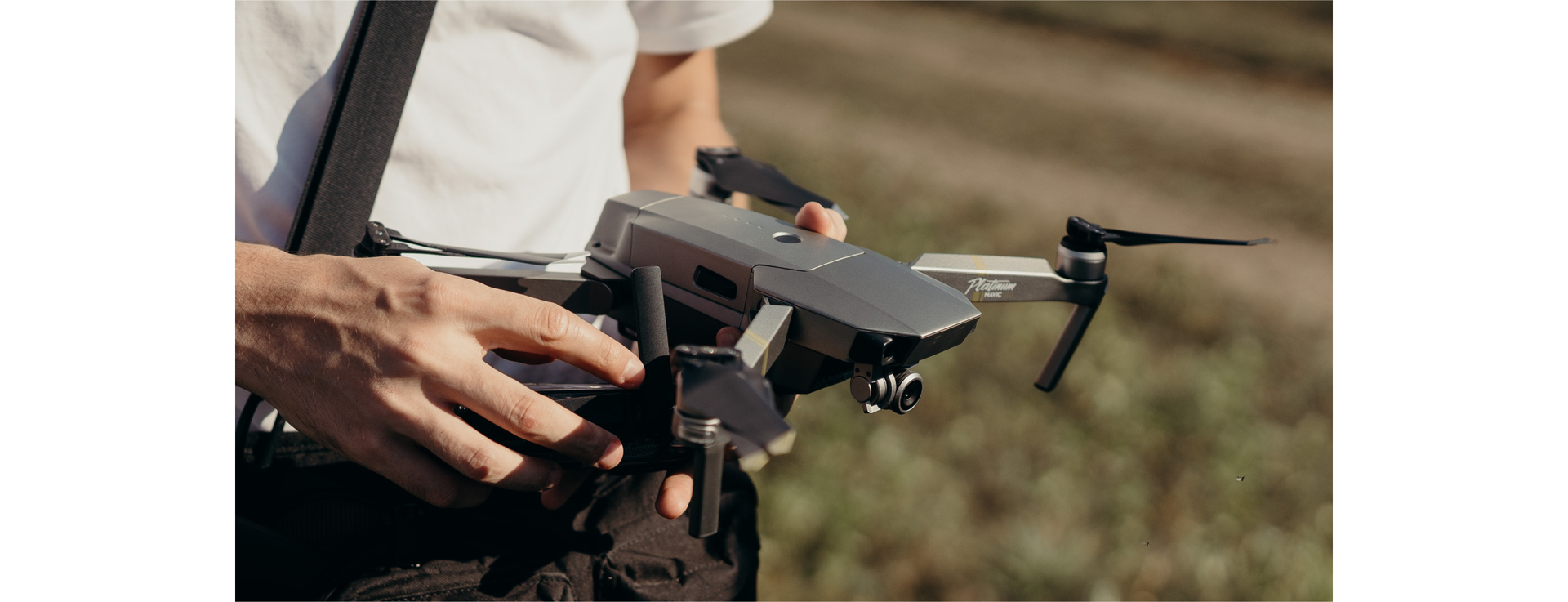 Zdjęcie przedstawia zbliżenie na ręce osoby, która trzyma drona.
