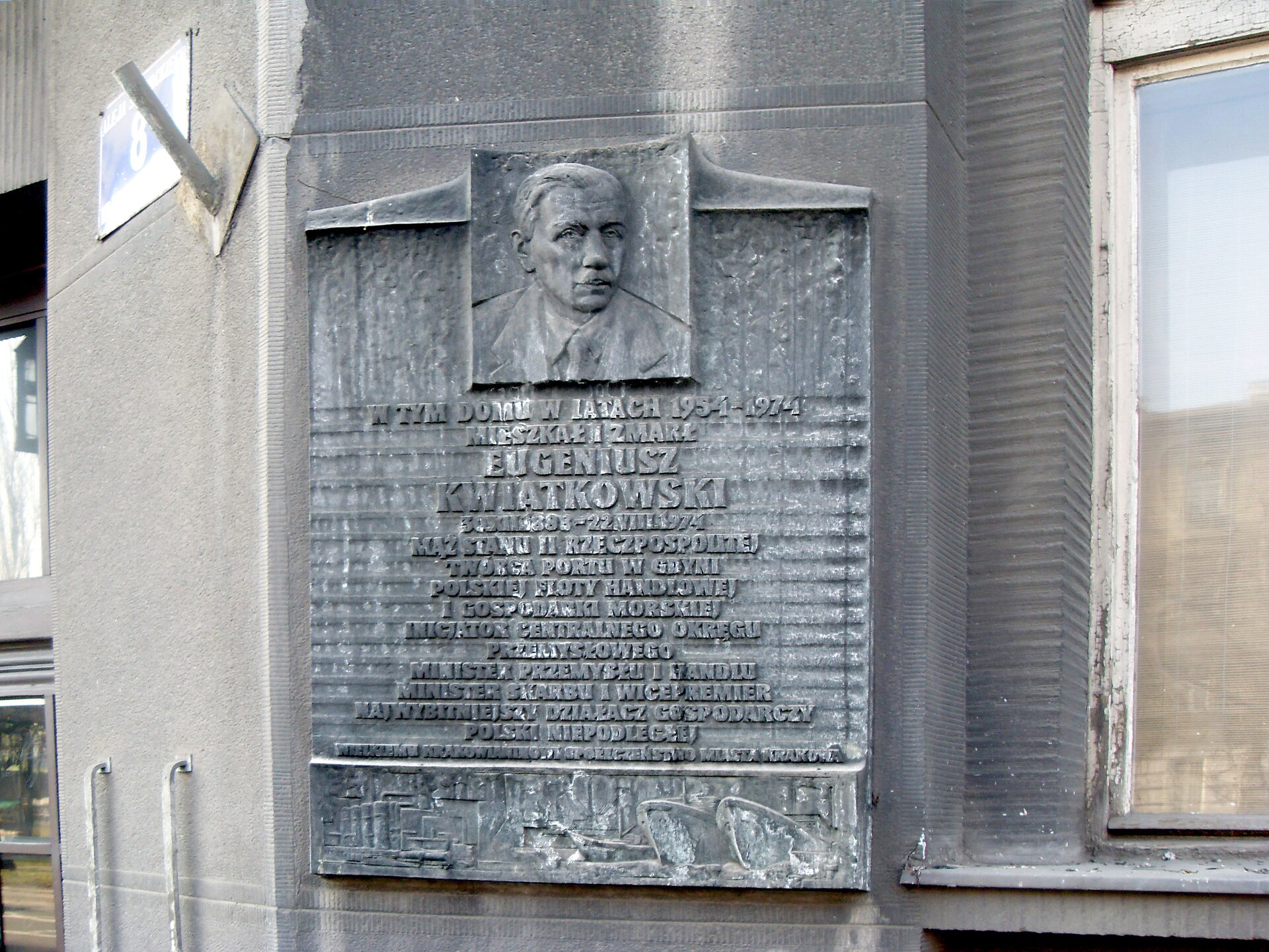 Kliknij żeby powiększyć Zdjęcie tablicy z popiersiem mężczyzny zawieszonej na ścianie kamienicy. Na tablicy napisano: W tym domu w latach 1954 - 1974 mieszkał i zmarł Eugeniusz Kwiatkowski. 30.XII.1888‑22.VIII.1974. Mąż stanu II Rzeczpospolitej. Twórca portu w Gdyni, polskiej floty handlowej i gospodarki morskiej. Inicjator Centralnego Okręgu Przemysłowego. Minister przemysłu i handlu. Minister skarbu i wicepremier. Najwybitniejszy działacz gospodarczy Polski niepodległej. Wielkiemu krakowianinowi społeczeństwo miasta Kraków.