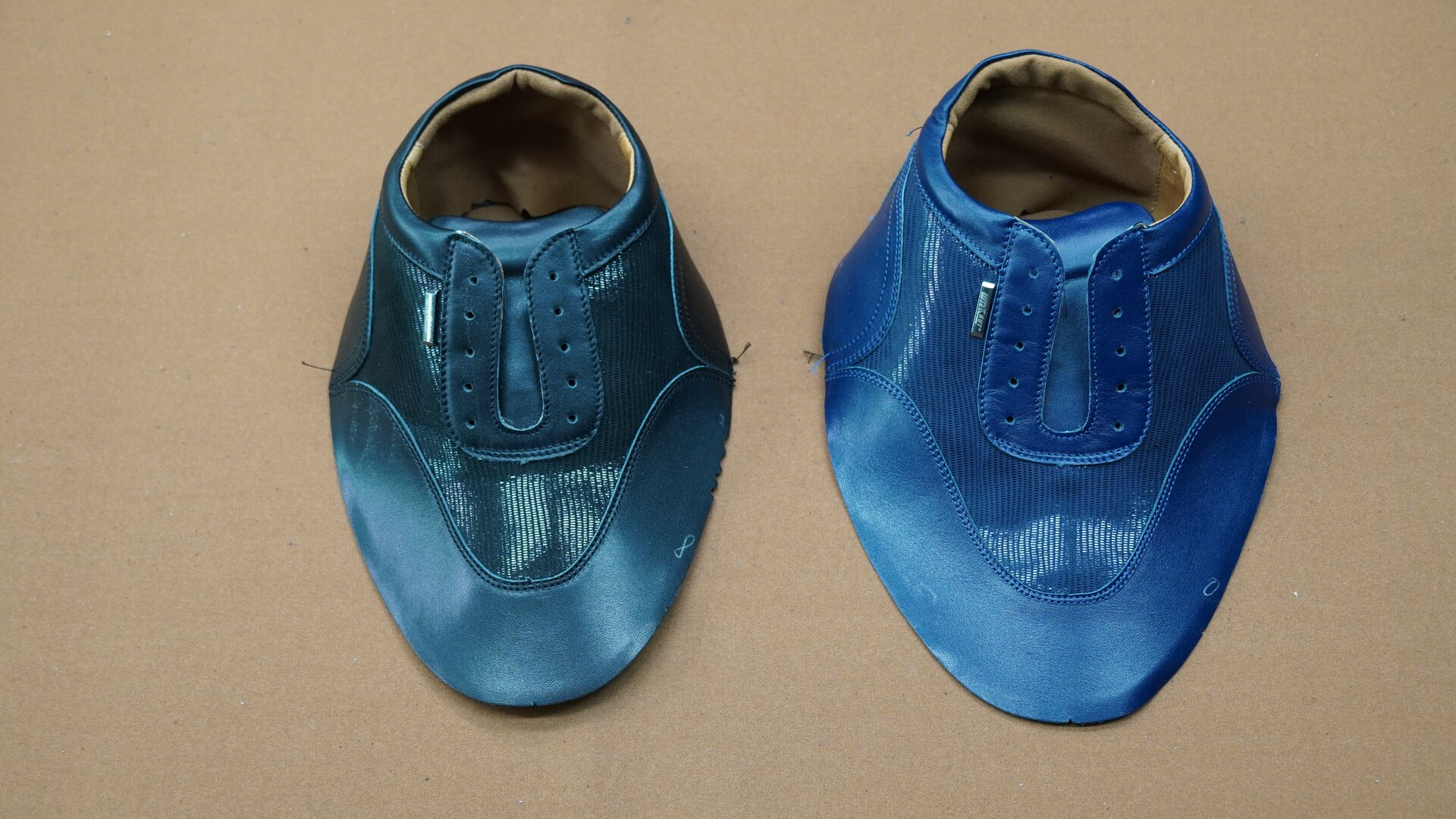 Zdjęcie przedstawia dwie cholewki przyszewkowe w kolorach czarnym i niebieskim. Widoczne są dziurki na sznurówki. Nagranie tożsame z treścią.