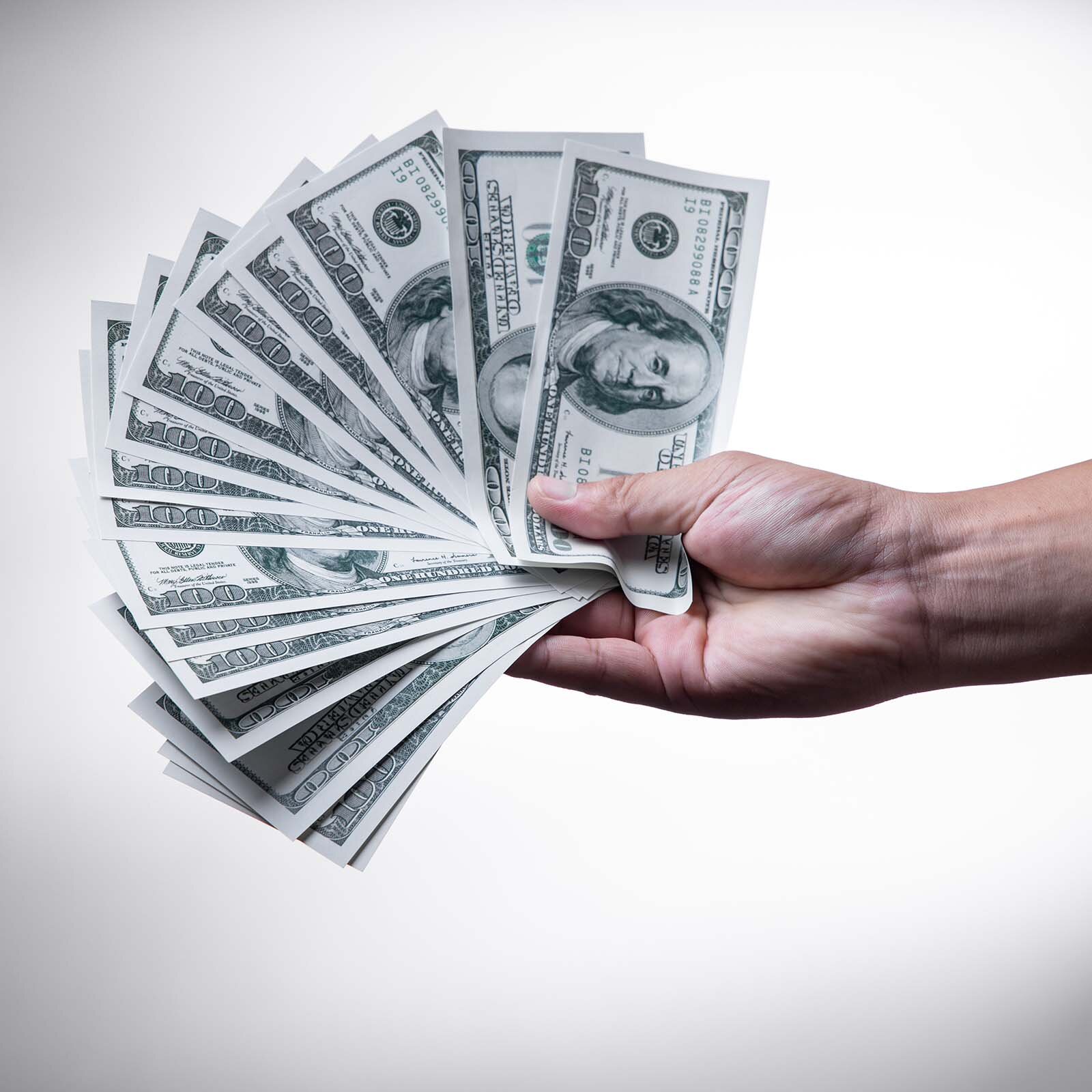 Zdjęcie ukazuje dłoń trzymającą wachlarz studolarówek.