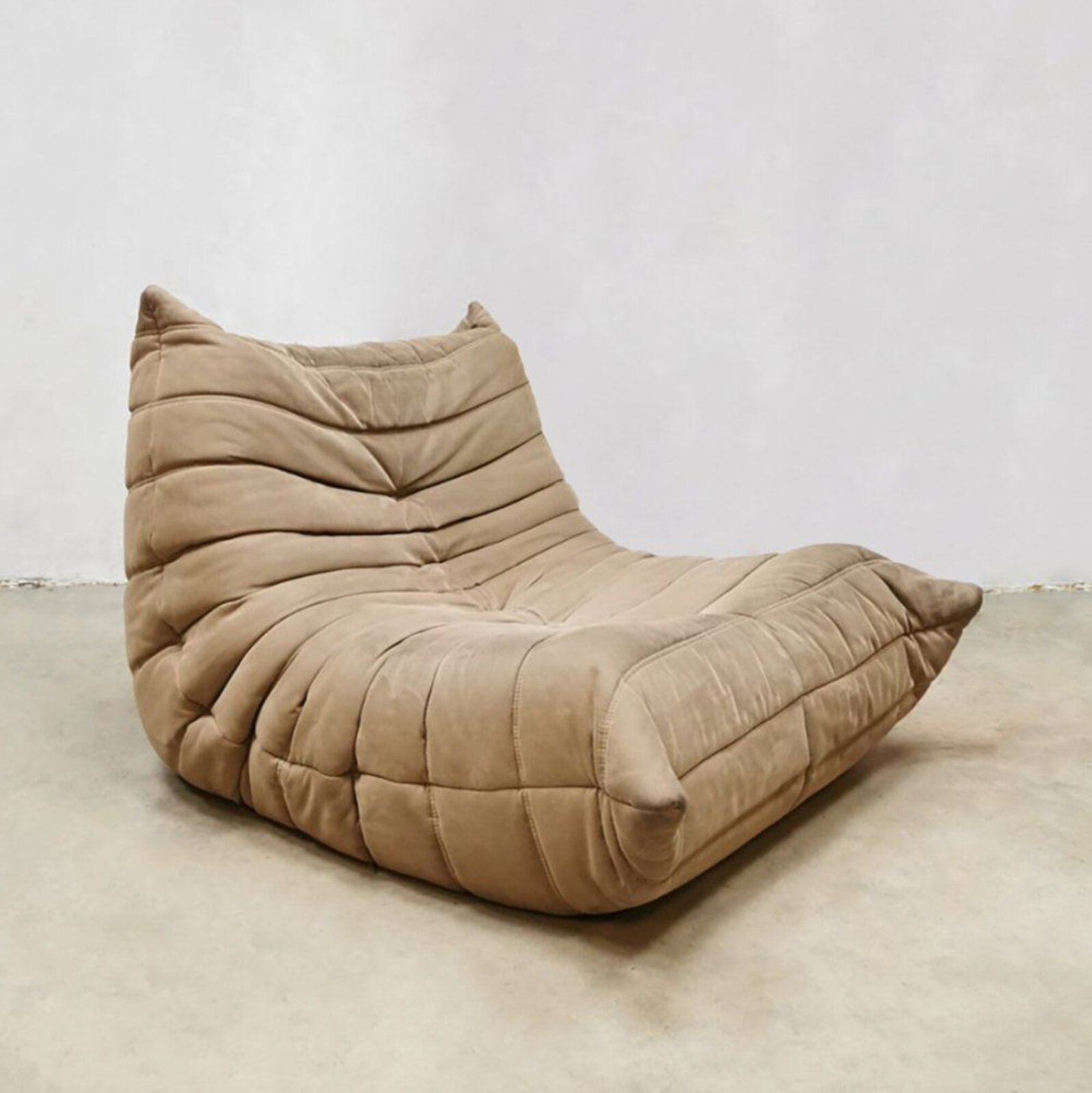 Ilustracja przedstawia pracę Michela Ducoroya pod tytułem „Sofa Tago”. W centrum fotografii umieszczono beżową sofę – mebel pozbawiony został nóg, jej konstrukcja oparta jest wyłącznie na wielu warstwach pianki i poliestru. Sofa Tago według konstruktora służy jednocześnie jako sofa, fotel i poduszka. Jej powierzchnia to zmarszczone warstwy beżowego materiału w ciepłym odcieniu, kształtem przypomina podstawę fotela. Umieszczono ją w pomieszczeniu o beżowej podłodze oraz białych ścianach.