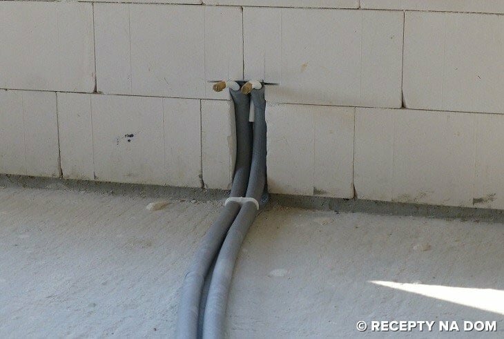 Zdjęcie ukazuje przewody instalacji grzewczej ułożone na posadzce i w ścianie. Jest to przewód zasilający i powrotny grzejnika ściennego.