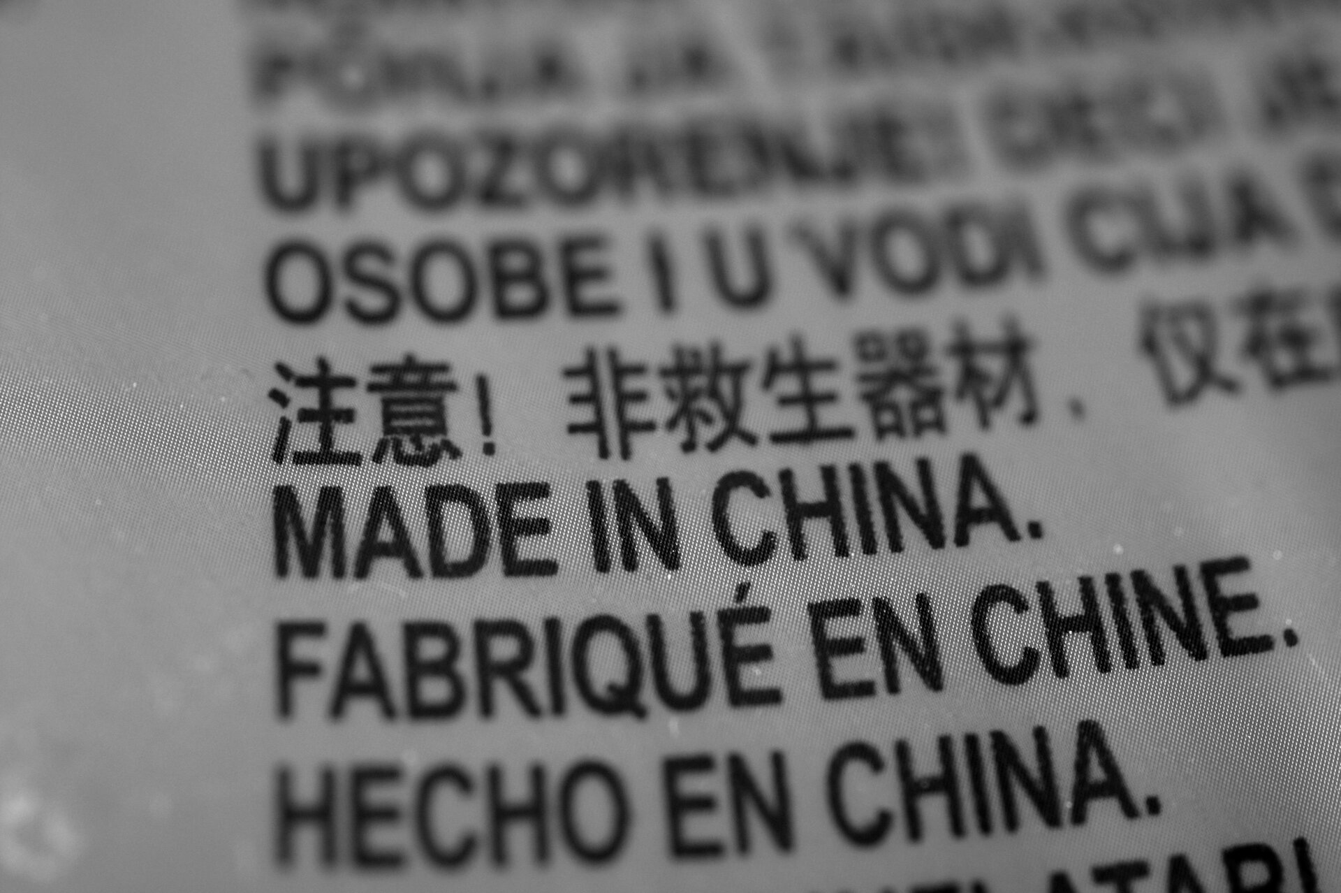 Ilustracja przedstawia fragment metki nieznanego produktu. Widnieje na niej napis: ‘MADE IN CHINA’. Napis ten jest przetłumaczony na kilka języków.
