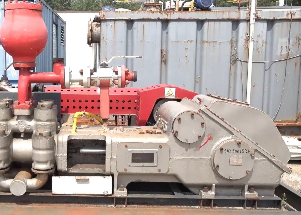 Zdjęcie przedstawia pompę płuczkową typu duplex. Urządzenie wykonane jest ze stali. U góry urządzenia widać czerwony  zbiornik ciśnieniowy w kształcie gruszki. Po lewej stronie urządzenia znajduje się stalowa obudowa. Dół pompy połączony jest rurą kołnierzową ze zbiornikiem.
Pompa płuczkowa odpowiada za zatłaczanie płuczki wiertniczej na dno otworu z odpowiednio wysokim ciśnieniem pozwalającym na pokonanie oporów przepływu i wyniesienie płuczki z fazą stałą (zwiercinami) na powierzchnię.  Widać również kompensator pulsacji po stronie wysokiego ciśnienia który służy do złagodzenia pulsacji powstających podczas pracy tłokowej pompy płuczkowej, która zasysa i tłoczy płuczkę strumieniem pulsującym. Powoduje to występowanie szkodliwych naprężeń dynamicznych w przewodzie tłocznym (pulsacji). Po stronie ssawnej pompy (niskiego ciśnienia) ma kształt walca z wewnętrznym rękawem gumowym wypełnionym gazem (azotem). Po stronie tłocznej pompy (wysokiego ciśnienia) ma kształt kuli z przeponą gumową wewnątrz. W celu dobrej amortyzacji powstającej pulsacji ciśnienie gazu nad przeponą powinno wynosić 2/3 ciśnienia tłoczenia pompy płuczkowej.