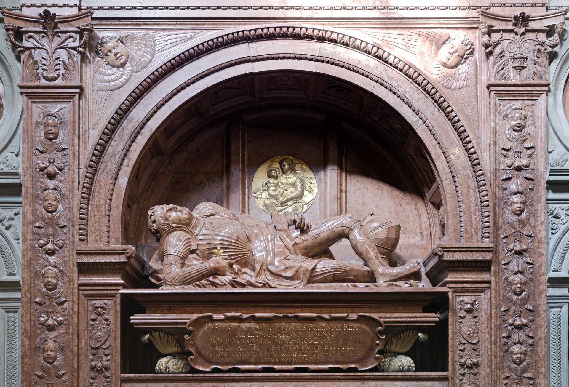 Ilustracja o kształcie poziomego prostokąta  przedstawia nagrobek Zygmunta I Starego wykonany przez Bartolomeo Berrecci, który znajduje się w Kaplicy Zygmuntowskiej w Krakowie. Postać leży w głębokiej niszy, podpierając się na prawym ramieniu. Lewą nogę ma przerzuconą nad prawą. Nisza zwieńczona jest łukiem i dekorowana po bokach pilastrami z głowami aniołków. Poniżej postaci znajduje się tablica z inskrypcją. 