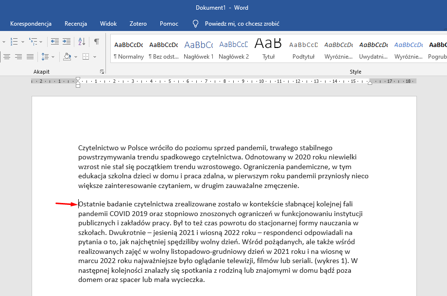 Na zdjęciu przedstawiono przykładowy dokument tekstowy w programie Word. W górnej części dokumentu widoczne są zakładki: Korespondencja, Recenzja, Widok, Zotero, Pomoc oraz Powiedz mi, co chcesz zrobić, a pod spodem znaki graficzne. Tekst dokumentu podzielony jest na dwa akapity. Kursor myszki umieszczony jest na początku drugiego akapitu, prowadzi do niego czerwona strzałka. 