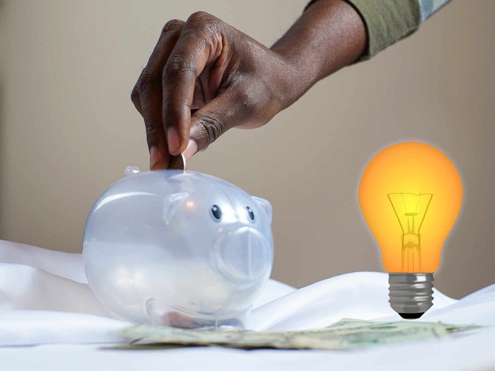 Na ilustracji widoczna jest przeźroczysta świnka skarbonka, do której ktoś wrzuca monetę. Z boku widoczna jest zapalona żarówka. Transkrypcja znajduje się poniżej