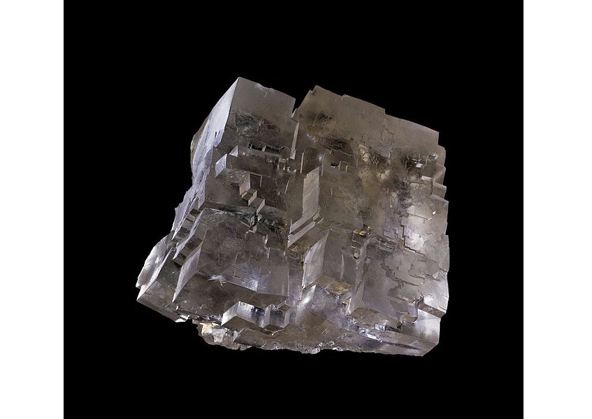 Zdjęcie przedstawia kryształ halit o kształcie sześcianu. Jego struktura charakteryzuje się regularnym ułożeniem jonów Cl minus i z wypełnieniem wolnych przestrzeni przez Na plus. Halit ma kolor półprzezroczysty i szarym odcieniem