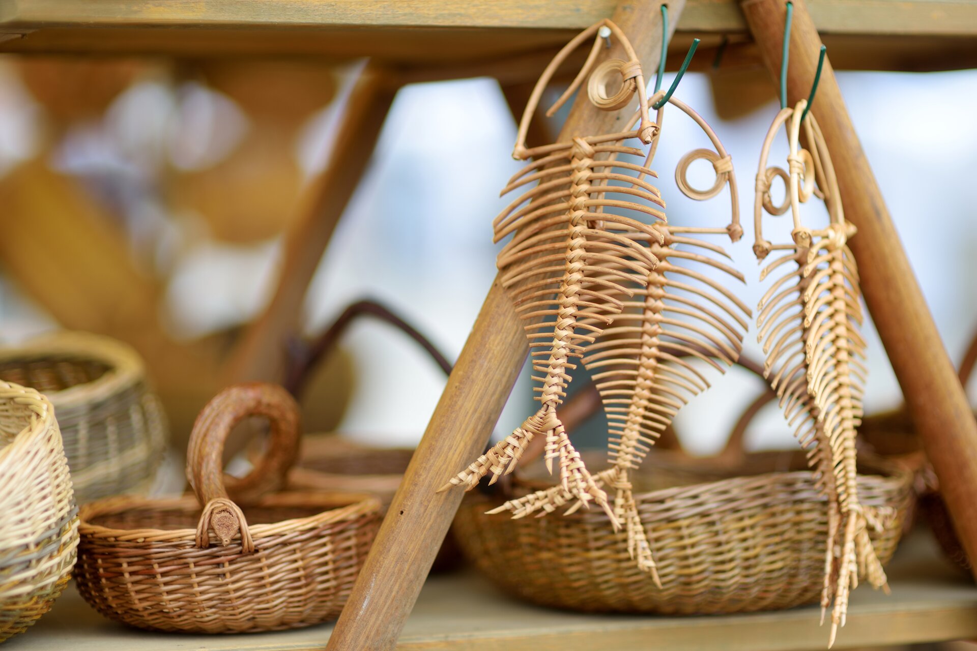Zdjęcie różnych wyrobów ułożonych na półce, koszyczków większych i mniejszych oraz ozdób w kształcie ryb.