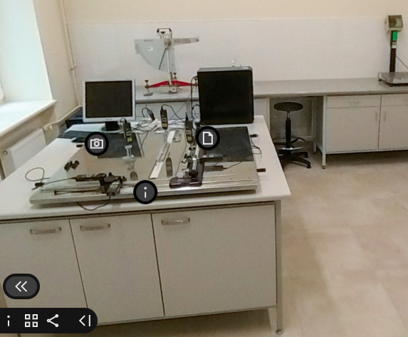 Grafika przedstawia przykładowy widok pochodzący z wycieczki wirtualnej przedstawiający wnętrze laboratorium. Widoczny jest stół laboratoryjny oraz umieszczone na nim sprzęty.
