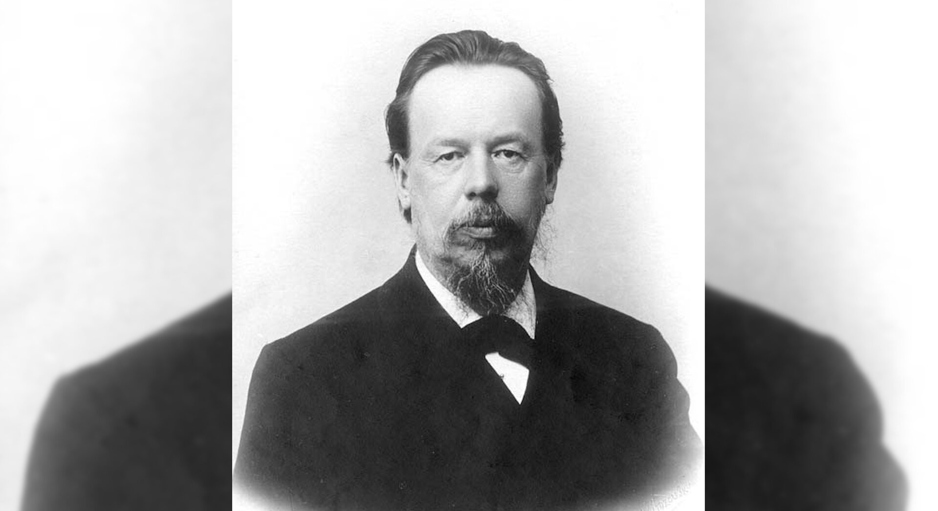 Fotografia czarno‑biała, przedstawiająca portret eleganckiego mężczyzny w marynarce.